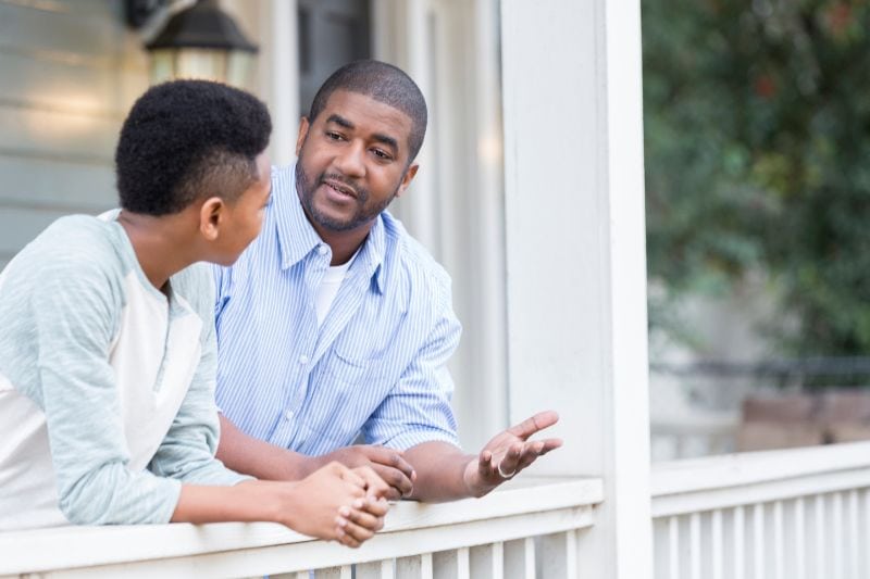 How Does a Gas Furnace Work? - Man Explains to His Friend How a Gas Furnace Works as They Lean on a Balcony.