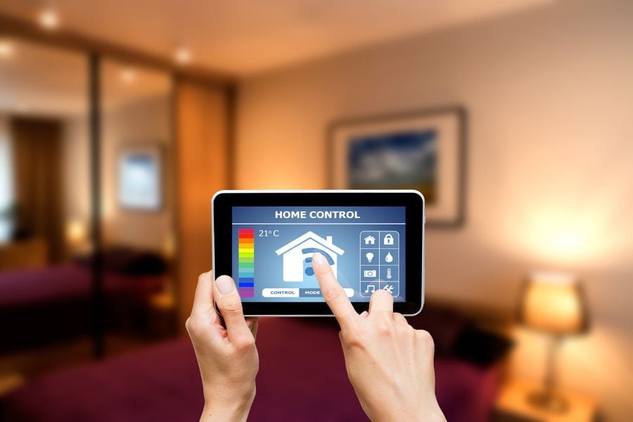Why Is My Thermostat Blank? Image shows two hands holding a thermostat remote in focus and the background is a living room out of focus.